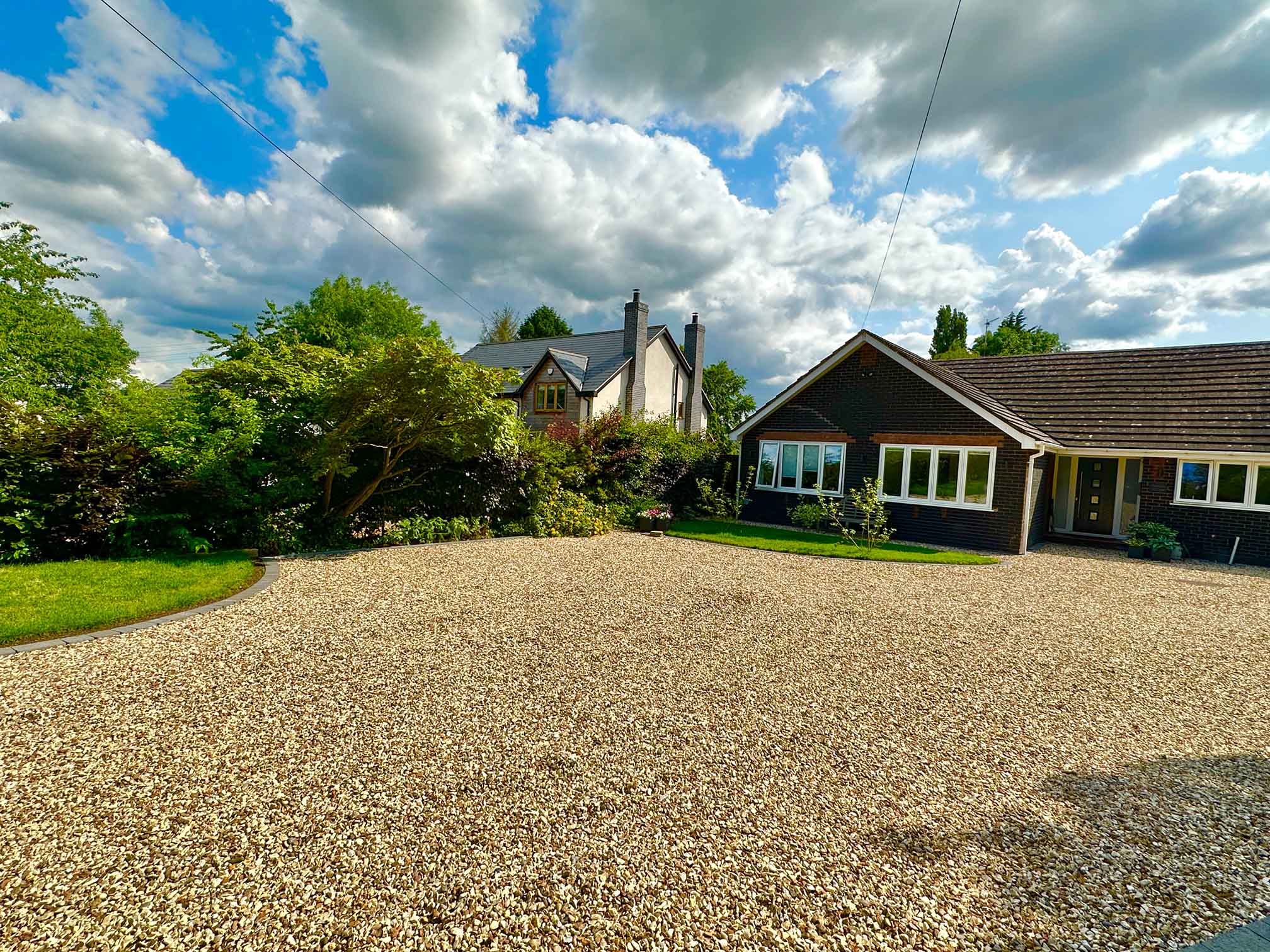A gravel driveway infront of a modern house